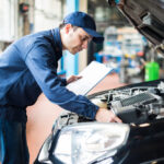 hombre revisando un auto negro para la revisión técnica