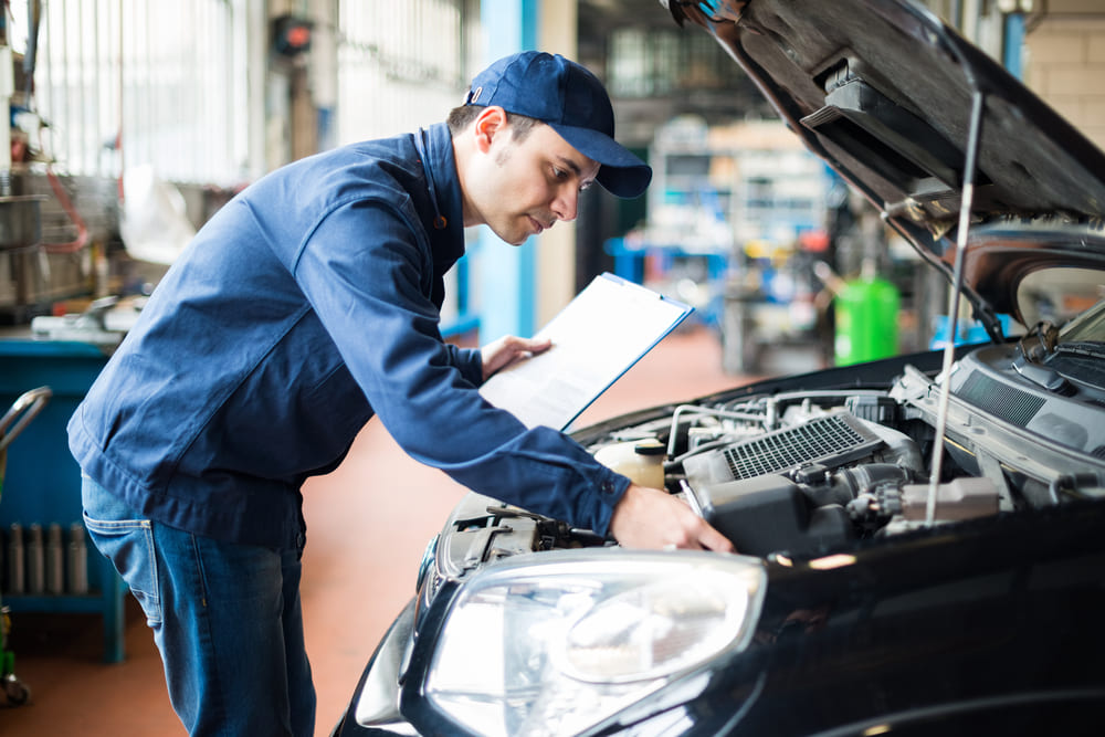 hombre revisando un auto negro para la revisión técnica