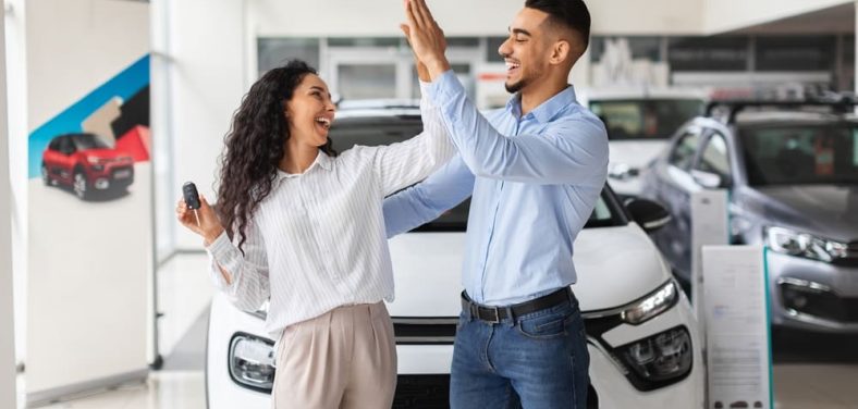 hombre y mujer chocando las manos manifestando alegría por comprar un auto