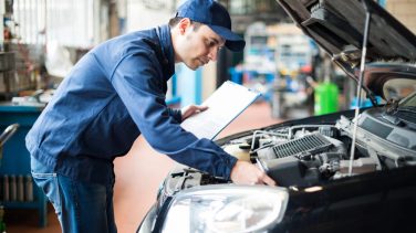 hombre revisando un auto negro para la revisión técnica