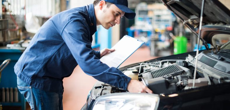 hombre revisando un auto negro para la revisión técnica